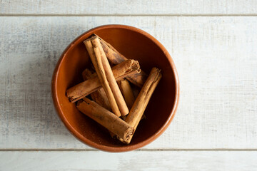 A top down view of several cinnamon sticks in clay bowl.