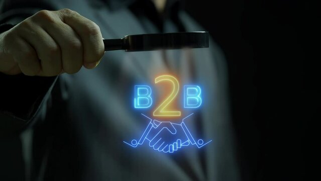 B2B marketing concept. business to business, e-commerce, Professional business and commerce collaboration. Businessman using magnifying glass focus on animation of hand shaking with B2B icon.