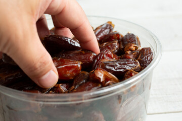 A view of a hand digging into a container of deglet noor dates.