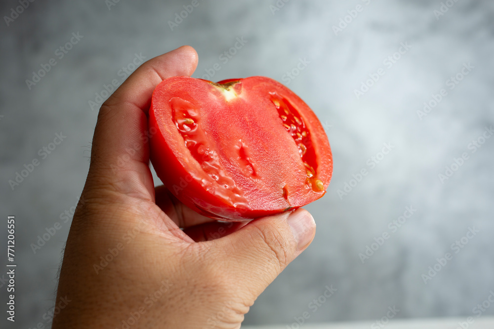 Wall mural a view of a hand holding a half tomato.