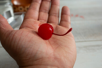 A view of a maraschino cherry in the palm of the hand.
