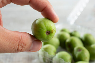A view of fingers holding a kiwi berries.