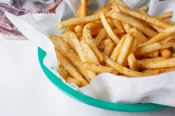 A closeup view of a basket of seasoned french fries.