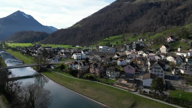 Drone clip of calm river with bridge, and mountainous village of Weesen, St Gallen, Switzerland
