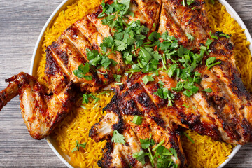 A top down view of a grilled whole chicken, atop a bed of yellow rice.