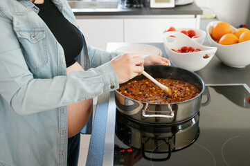 Pregnant woman with big belly cooking at home