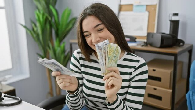 A smiling young woman holds peruvian soles in a modern office, suggesting finance or savings.