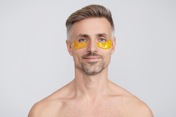 Eye patch. Beauty man face with under eye collagen pads. Mature man has fresh healthy skin with collagen patches under eyes. Facial treatment. Man applying eye patches. Spa care. Skincare routine
