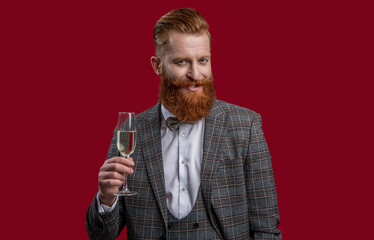 Cheers. Bearded man with formal look. Celebrate with champagne. Cheering and celebrating. Elegant tuxedo man hold glass of champagne isolated on red. Celebrating success. Cheering with champagne