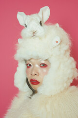 Woman wearing white furry hat with rabbit on top of head, looking stylish and cute