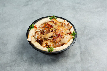A view of a bowl of hummus topped with chicken shawarma.