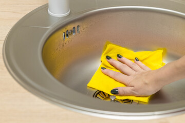 woman washing the sink in the kitchen, close up.