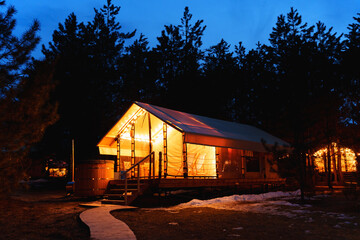 Glamping from tent houses in the forest in the dark. 