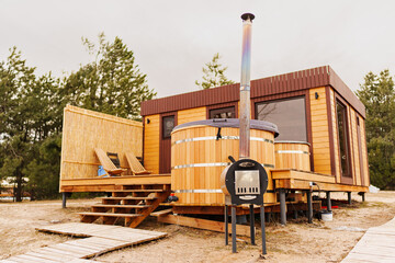 A glamping house with a swimming hot tub in a pine forest. 