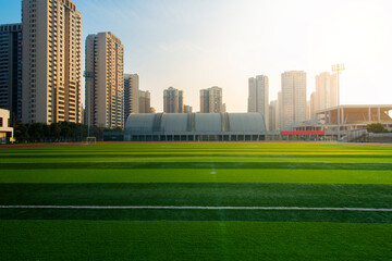 In the city, sunlight shines on outdoor sports stadiums, and outside the stadiums are towering skyscrapers