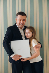 A dad and daughter hold a photo book in a white leather cover 