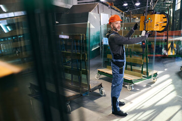 Male using a vacuum lifting device in a window factory