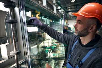 Worker uses special tools to work with glass in window production