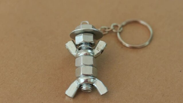 Silver keychain crafted to resemble a figure with hat, made from nuts and bolts