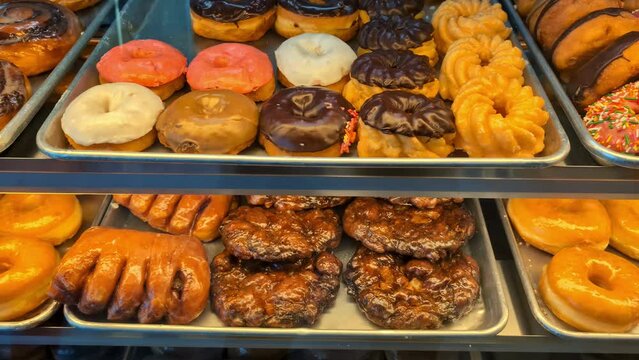 Closeup shot to a display full of sweet snacks donuts pastry under store lights