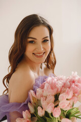 Portrait of smiling woman in violet dress with bouquet of tulips