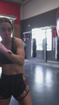 Focused young ethnic sportswoman training with boxing ball.