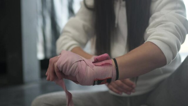 Unrecognizable woman putting boxing tape around palm.