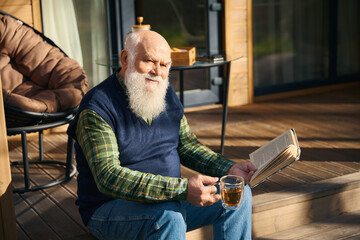 Cute old man sitting with a book on the porch