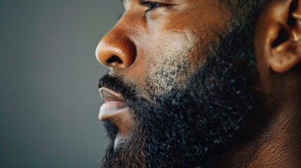 side view profile portrait of  a black man with a long full beard on a studio background