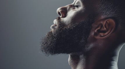 side view profile portrait of  a black man with a long full beard on a studio background