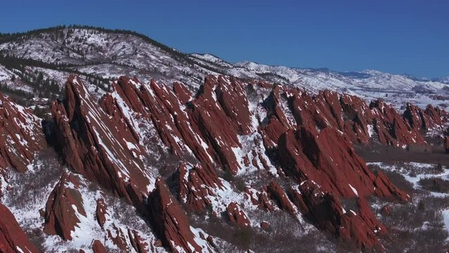 Stunning March winter morning snow  Roxborough State Park Littleton Colorado aerial drone sharp jagged dramatic red rock formations Denver foothills front range landscape blue sky backwards motion
