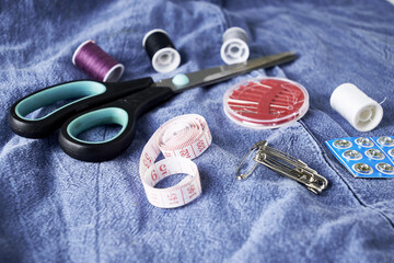 scissors needles measuring tape and thread on the background of torn jeans the concept of reasonable consumption of needlework for small businesses - obrazy, fototapety, plakaty