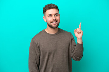 Young caucasian man isolated on blue background showing and lifting a finger in sign of the best - 771277365