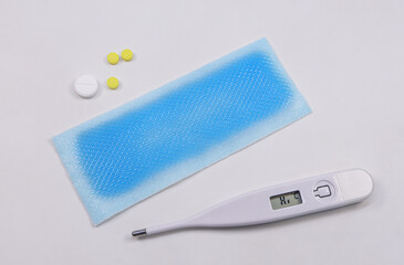 Medical digital thermometer, Cooling fever patch gel and medicinal pills on white background. basic...
