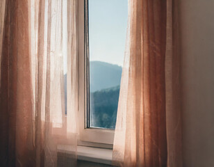 Backlit window with delicate beige-pink translucent curtains in an empty room. Peach fuzz color