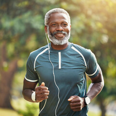 Happy black man running in the park with music, smile, and mockup in nature, Senior male, outdoor runner and motivated for fitness, energy and healthy exercise training with earphones.