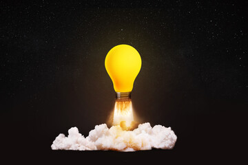Creative light bulb rocket with blast and smoke takes off on a black background, concept....