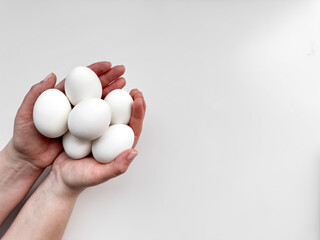 Hands cradling a cluster of white eggs against pale background, a symbol of care, nourishment, and new beginnings with ample copy space. For culinary websites, recipe blogs, and nutritional guides.