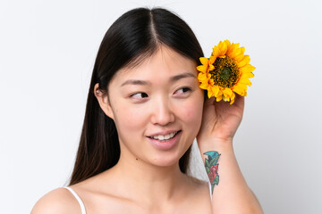 Young Chinese woman isolated on white background holding a sunflower while smiling. Close up portrait