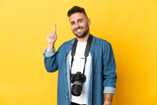 Photographer man isolated on yellow background pointing up a great idea