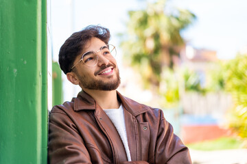 Handsome Arab man at outdoors looking up while smiling
