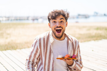 Handsome Arab man holding sashimi at outdoors with surprise and shocked facial expression
