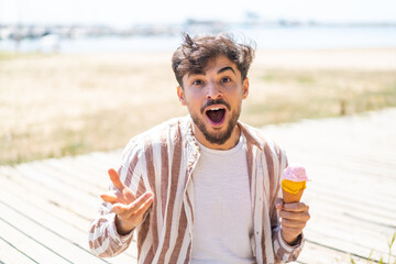 Handsome Arab man with a cornet ice cream at outdoors with shocked facial expression - obrazy, fototapety, plakaty