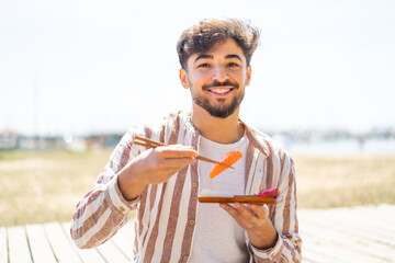 Handsome Arab man at outdoors holding sashimi