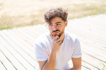 Handsome Arab man at outdoors With glasses and having doubts