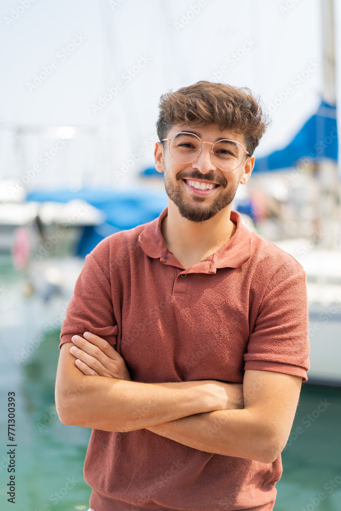 Wall mural young arabian handsome man at outdoors with his arms crossed