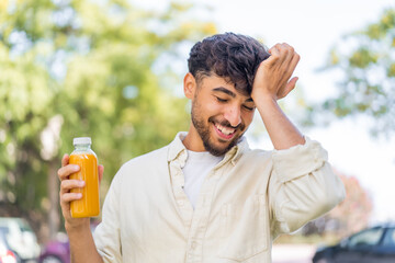 Young Arabian handsome man holding an orange juice at outdoors has realized something and intending...