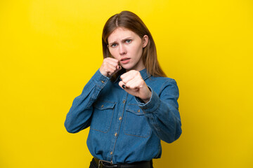 Young English woman isolated on yellow background with fighting gesture - obrazy, fototapety, plakaty