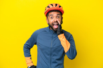 Young cyclist Brazilian man isolated on yellow background shouting with mouth wide open