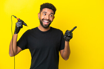 Tattoo artist man Brazilian man isolated on yellow background intending to realizes the solution while lifting a finger up - obrazy, fototapety, plakaty